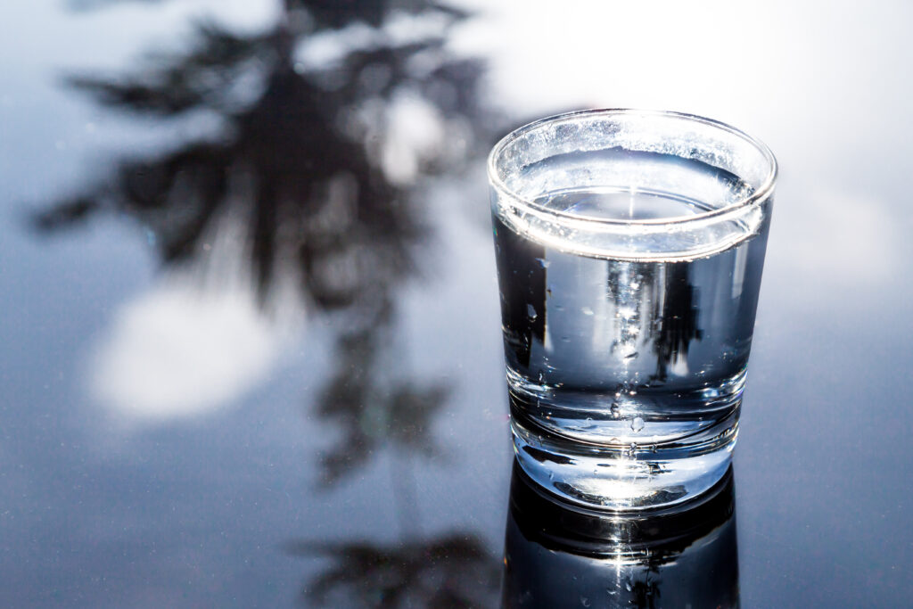 refreshing water in transparent glass with reflection against bl