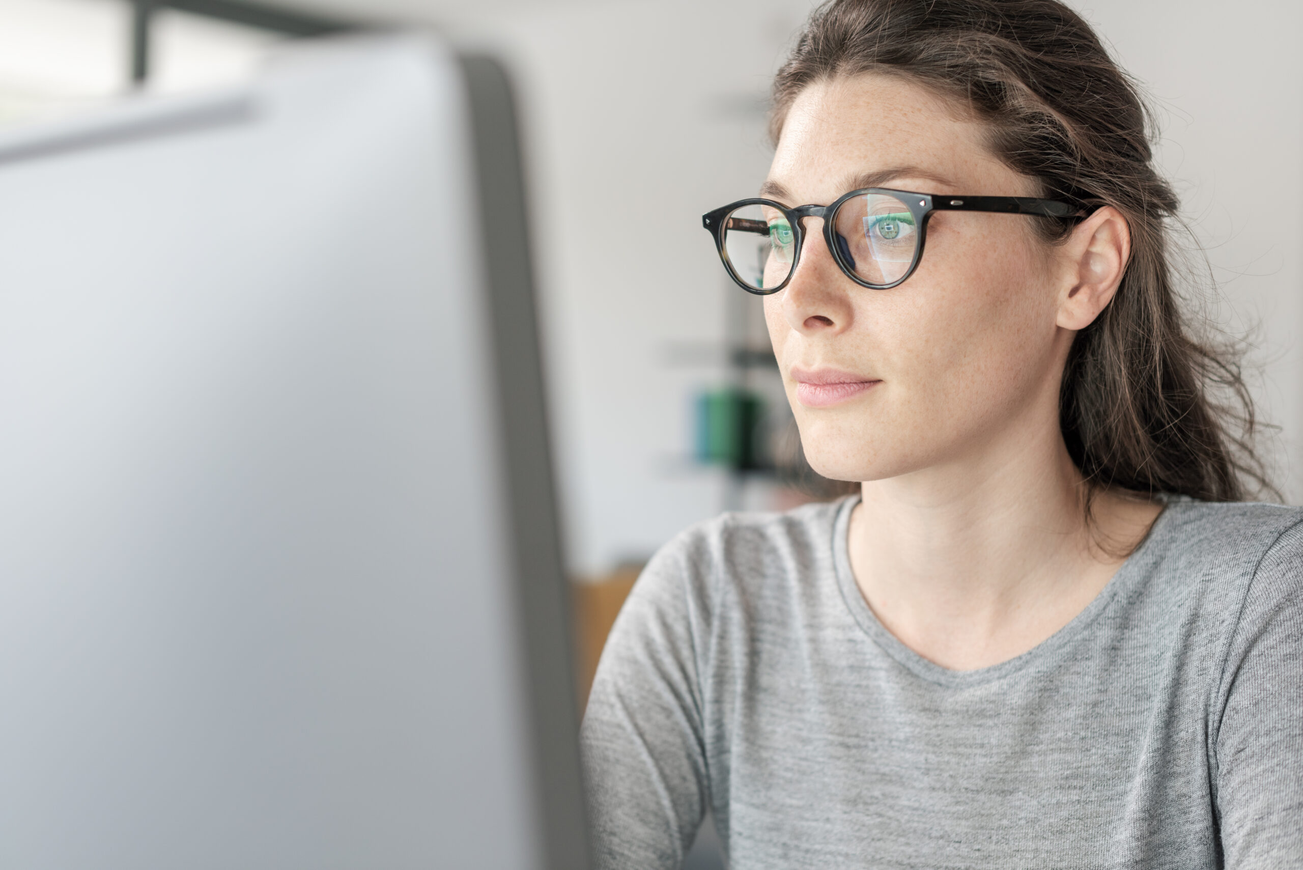 woman with glasses working on a computer